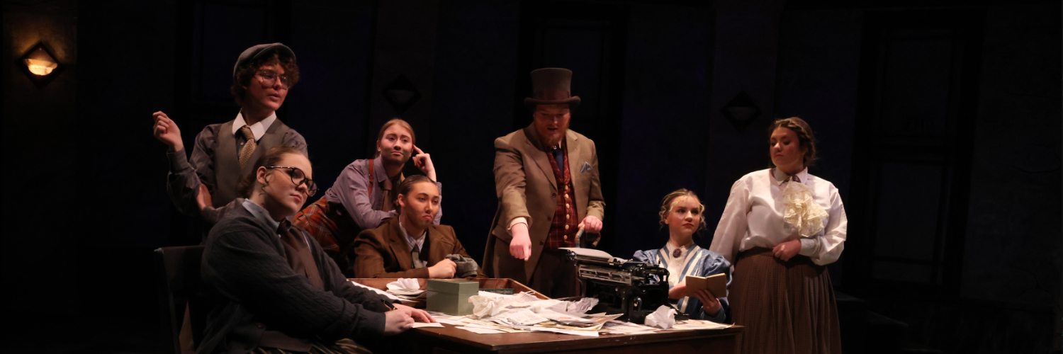 People from An Enemy of the People standing around a destk