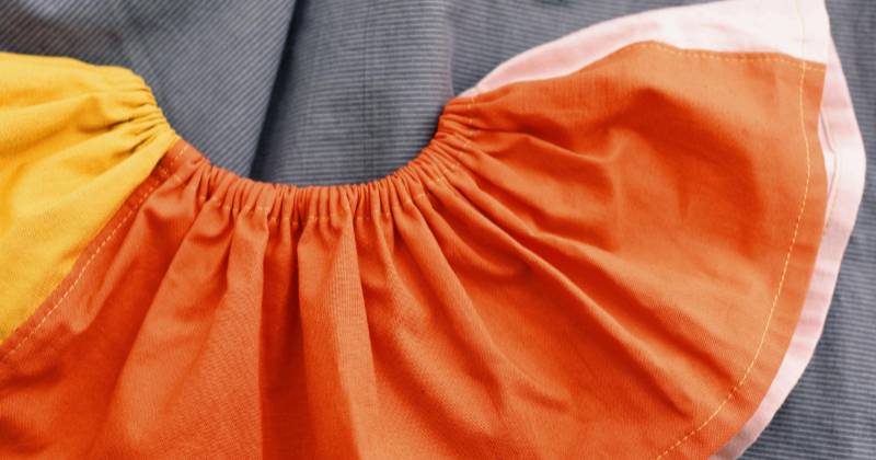 A colorful elastic waisted skirt sitting on a blue background.
