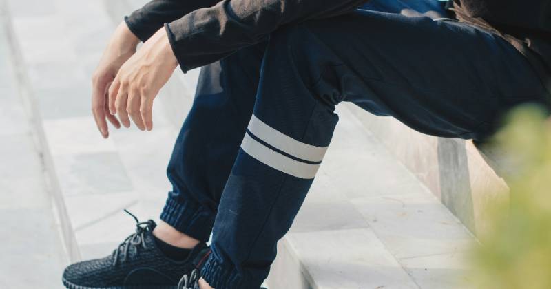 Sitting person in joggin pant, showing legs only.